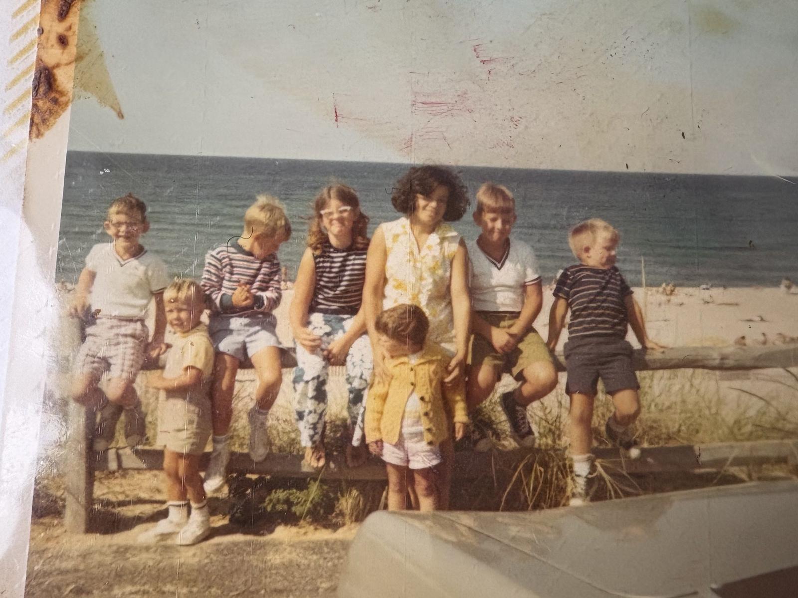 A family of children sitting on a beach fence in their summer clothes